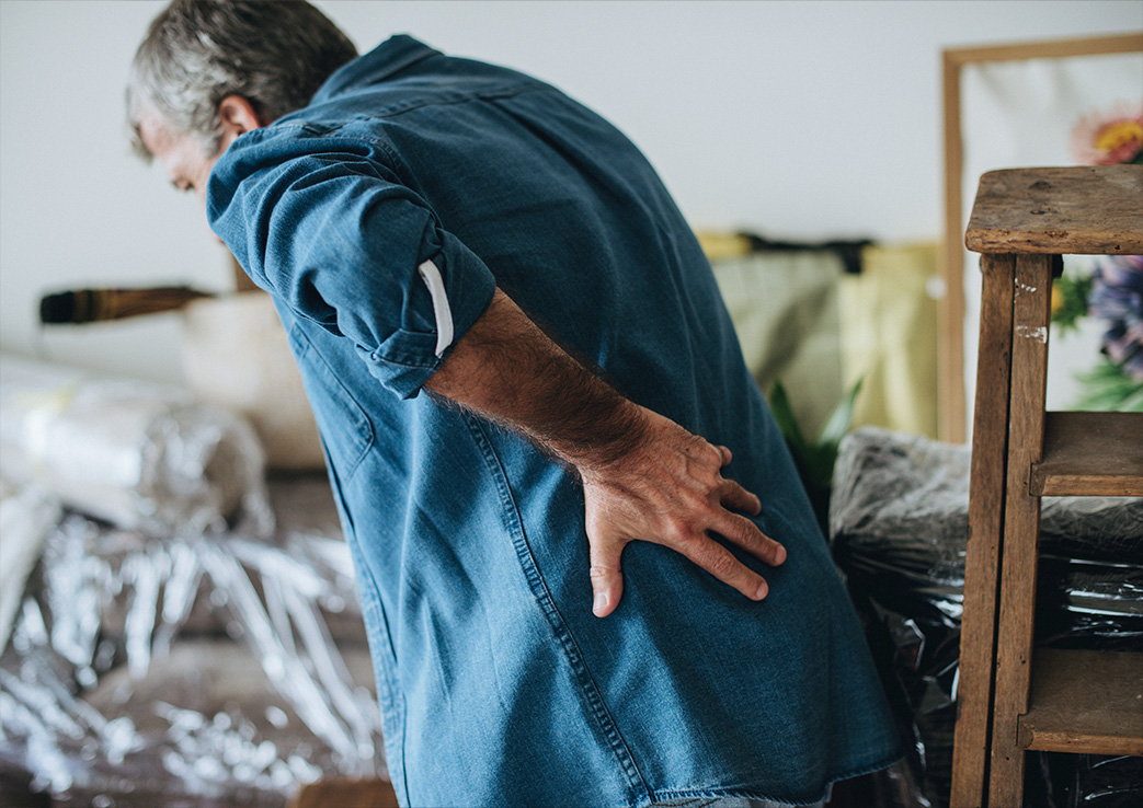 Mann mit Rückenschmerzen im unteren Rückenbereich als Symbol für chronische Schmerzen und Silent Inflammation in der ganzheitlichen Schmerztherapie.